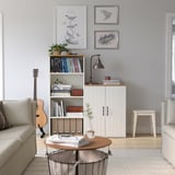 Living room with SKRUVBY sideboard, guitar, bookshelf, coffee table, two sofas, lamp, and oak-finished furniture against a light blue wall.