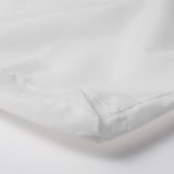 A close-up of a white, neatly stitched fabric corner, showcasing its texture and quality.