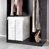 Black wardrobe with white laundry bag for clothes storage.
