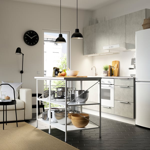 Modern kitchen with white cabinets, black pendant lights, and a metal kitchen island holding pots and wooden bowls.