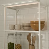 Modern open kitchen shelves with integrated led lighting featuring bowls, cups, jars, and wooden utensils.