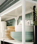 White kitchen shelf with bowls, vases, and plant. Modern, minimalist design.