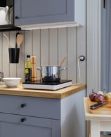 Modern kitchen with induction cooktop and wooden counter.