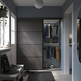 Modern closet with SKYTTA gray doors, clothes, & accessories. Mirror reflects plants.