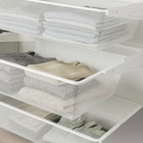 White mesh storage drawer pulled out, filled with folded clothes, showing organizing function.