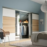 Modern blue bedroom with gray bed, SKYTTA mirrored closet door, clothes visible.