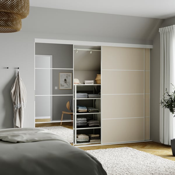 Modern bedroom with large SKYTTA sliding closet in beige and grey. Mirrored panels, neat clothes, wicker pendant light above bed.