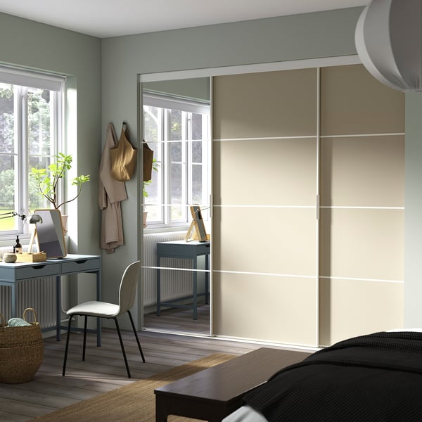 Modern room with SKYTTA wardrobe, mirrored doors, desk by window, plants and decor.