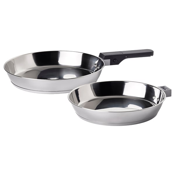 Silver frying pans, minimalist design, one with black handle, stackable, durable stainless steel.