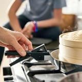 Person is removing handle from pan on stove. Pan is part of SLÄTROCKA cookware set, which detachable handles for space-saving and versatility.
