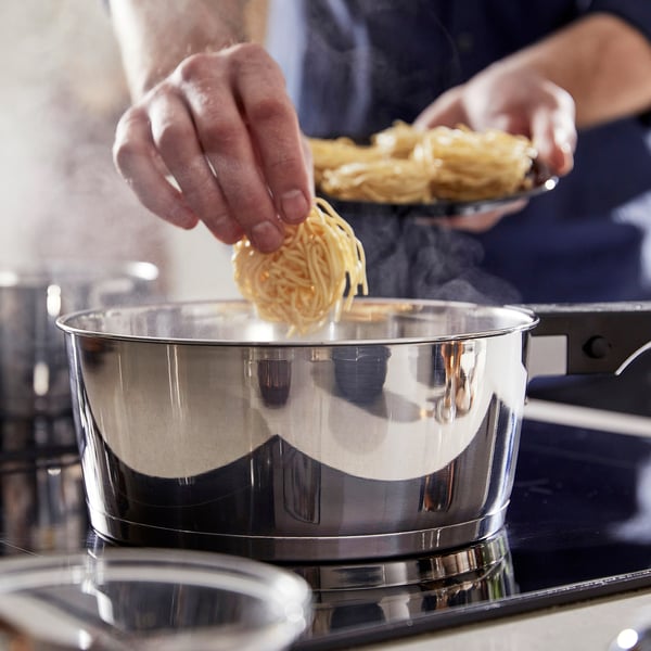 A person is using a SLÄTROCKA saucepan with a detachable handle, demonstrating its easy handling and space-saving feature.