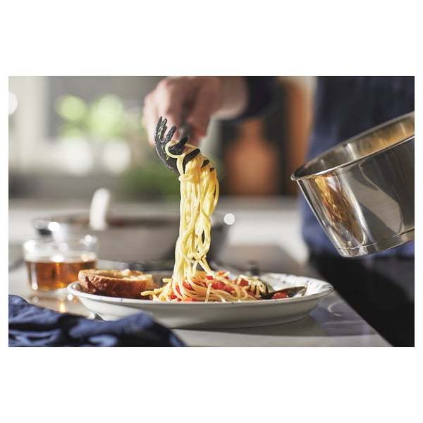 Person cooking spaghetti in pots; kitchen setting.
