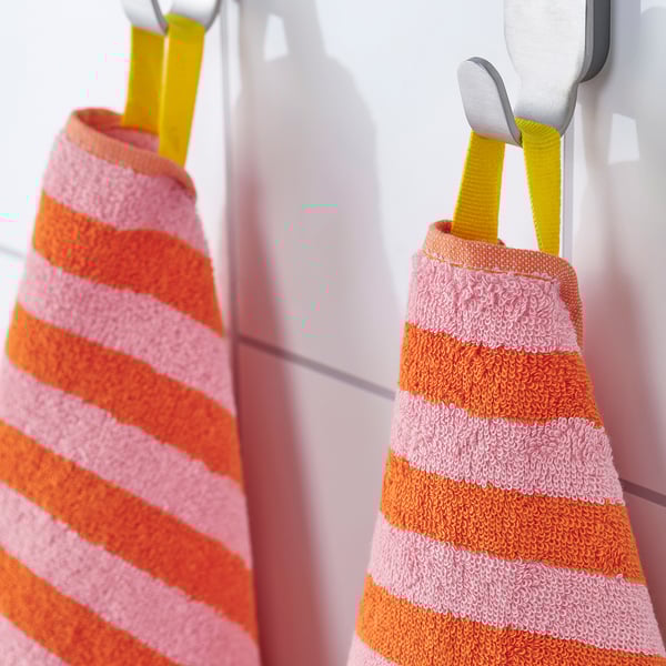 Orange and pink striped towels hang on white wall hooks, 100% cotton, absorbent.