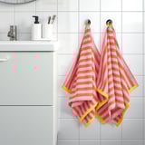 Bathroom with orange & yellow towels beside white sink and grey cabinet.