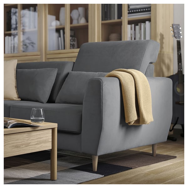 Modern grey SLATORP sofa with wooden legs, cozy blankets, and wine glass on a coffee table.