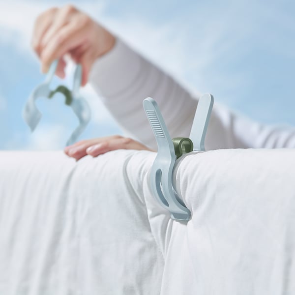 Person holding white clothes with large blue heavy-duty laundry pegs.