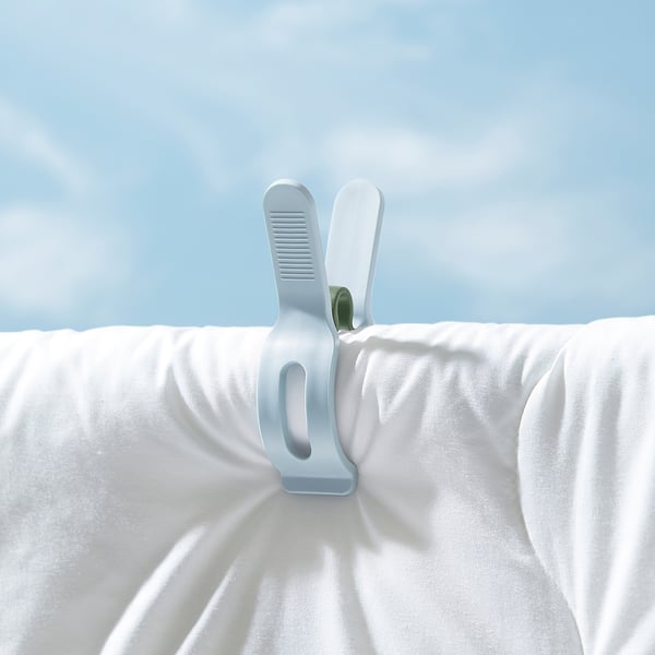 Two white laundry pegs clipping fabric, ideal for heavy items, uv-resistant plastic, robust grip.