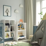 Childrens room with SMÅGÖRA white shelves, light blue accents, & playful decor. A changing table, books, toys, & a tent.