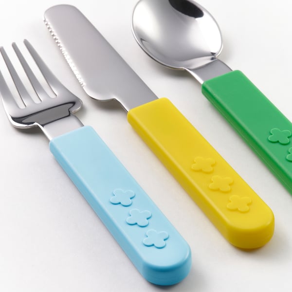 Childrens utensils: colorful, serrated knife, fork, and spoon, designed for easy grip and learning.