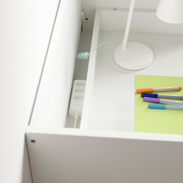 Childs white desk with open drawer and pen tray, holding colorful markers and a notepad.