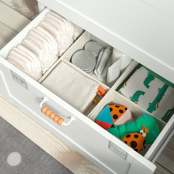 Open white SMÅSTAD drawer with diapers, wipes, blankets, dinosaur print, and colorful toys neatly organized.