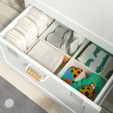 Open white SMÅSTAD drawer with diapers, wipes, blankets, dinosaur print, and colorful toys neatly organized.