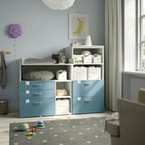 SMÅSTAD blue storage unit with shelves, larger than surrounding toys, holds white bins, cloths, books.