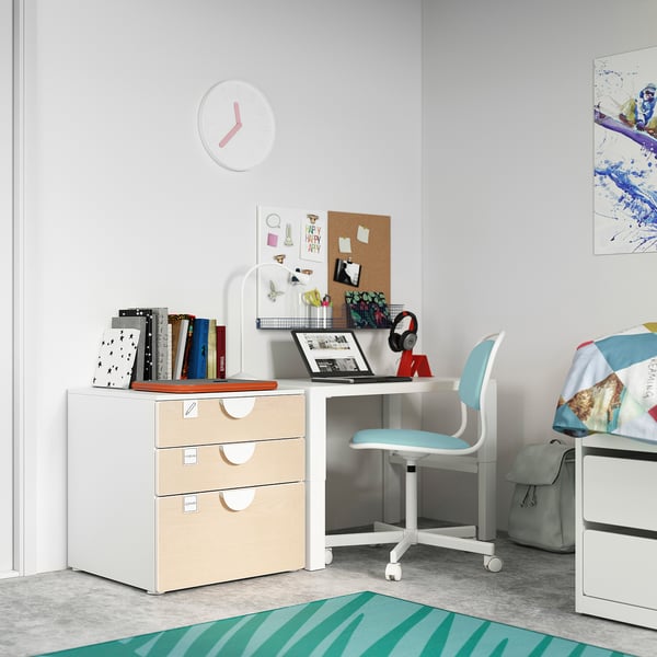 Childs study area with white desk, blue chair, and colorful decor. Includes books, laptop, and clock.