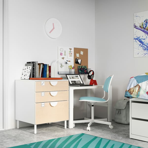 Childrens room with white SMÅSTAD desk, light blue chair, wooden drawers. Laptop, books, colorful decor.