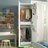 Childs room with white SMÅSTAD wardrobe, wooden shelves, desk, and colorful decor.