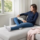 A woman reads a book on a cozy sofa with high resilience cushions and comfortable armrests, designed for comfort and durability.