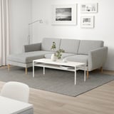 A modern living room with a gray chaise sofa, coffee table, and photos, creating a cozy, minimalistic atmosphere.