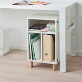 White storage unit with adjustable legs, holding books, toys, and a plastic box, designed for a childs room.