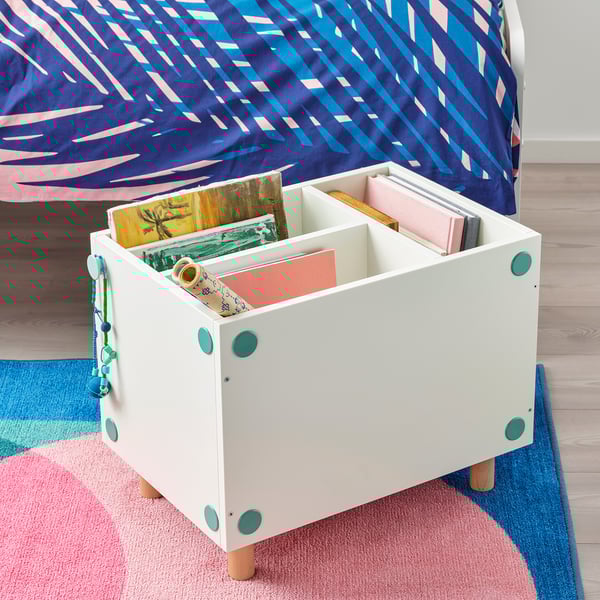 White storage box under a bed, holding colorful books. The box has turquoise circular handles and adjustable legs for different bed heights.