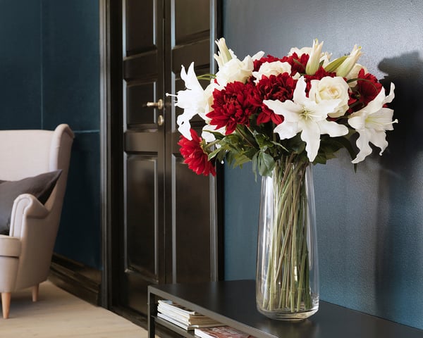 Vase with red and white flowers on dark table, elegant design.