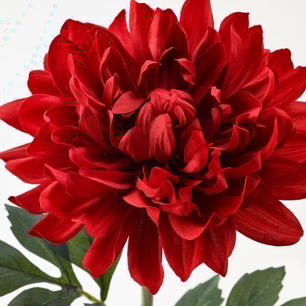 Lifelike red artificial flower with green leaves, vivid and detailed petals, realistic texture.