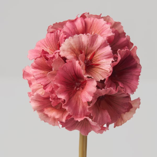 Large, vibrant pink artificial flower with ruffled petals, attached to a green stem.