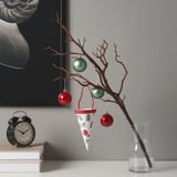Holiday branch with baubles, books, alarm clock, and wall art.