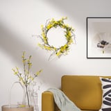 Yellow sofa, floral wreath, vase with flowers on table, white flower art.