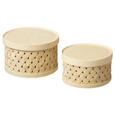 Two light-colored, round woven baskets with lids, stacked side by side.