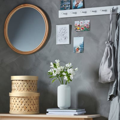 A stylish, natural-woven poplar SNÖPLOG basket in tan, fitting neatly on a shelf, holding belongings.