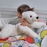 Child hugging a large white polar bear plush toy in bed, offering comfort and warmth.