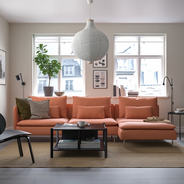 Modern living room with SÖDERHAMN orange sectional sofa, large white pendant lamp, coffee table, plant, and large windows.