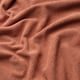 Close-up of rust-red, soft, textured fabric with wavy lines, showcasing high-quality material.