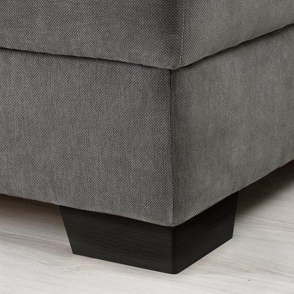 Close-up of a modern, grey fabric sofa with square, dark wooden legs.