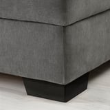 Close-up of a modern, grey fabric sofa with square, dark wooden legs.
