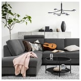 Grey sofa with pillows, coffee table, light fixture, rug, and guitar.