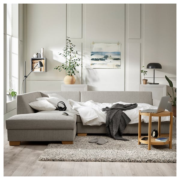 Gray sofa, white rug, side table, lamp, plants, art, headphones, cozy home.