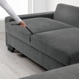 Person opens SÖRVALLEN sofas storage compartment, revealing hidden space.