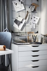 Modern office setup with white SÖSDALA memo board displaying notes and photos. Includes metal wire basket with writing tools on a white desk.
